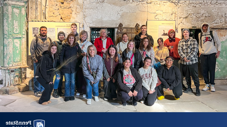 a group of students and teachers smile as a group while touring an old prison